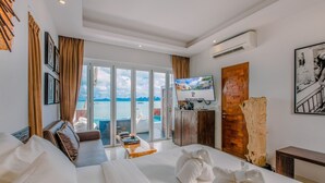 A hotel room with a large bed, a television, a wooden cabinet, and a view of the sea. - The Privilege Hotel Ezra Beach Club (Koh Samui)