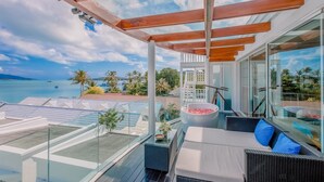 A modern outdoor lounge area with a glass balustrade, a pool table, and a seating area with cushions. - The Privilege Hotel Ezra Beach Club (Koh Samui)