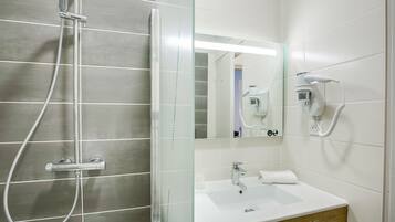 A modern bathroom with a glass shower enclosure, a white sink, and a hairdryer mounted on the wall.