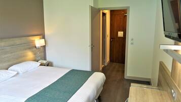 Une chambre d’hôtel équipée d’un lit, d’une lampe de chevet et d’un téléviseur fixé au mur.