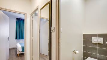 A bathroom with a toilet, a shower, and a mirror.