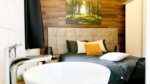 Un baño moderno con un lavabo blanco grande, un cabecero color beige y un mural en la pared con motivos de bosque.