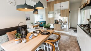 Una cocina moderna con una mesa de madera, sillas blancas e iluminación colgante.