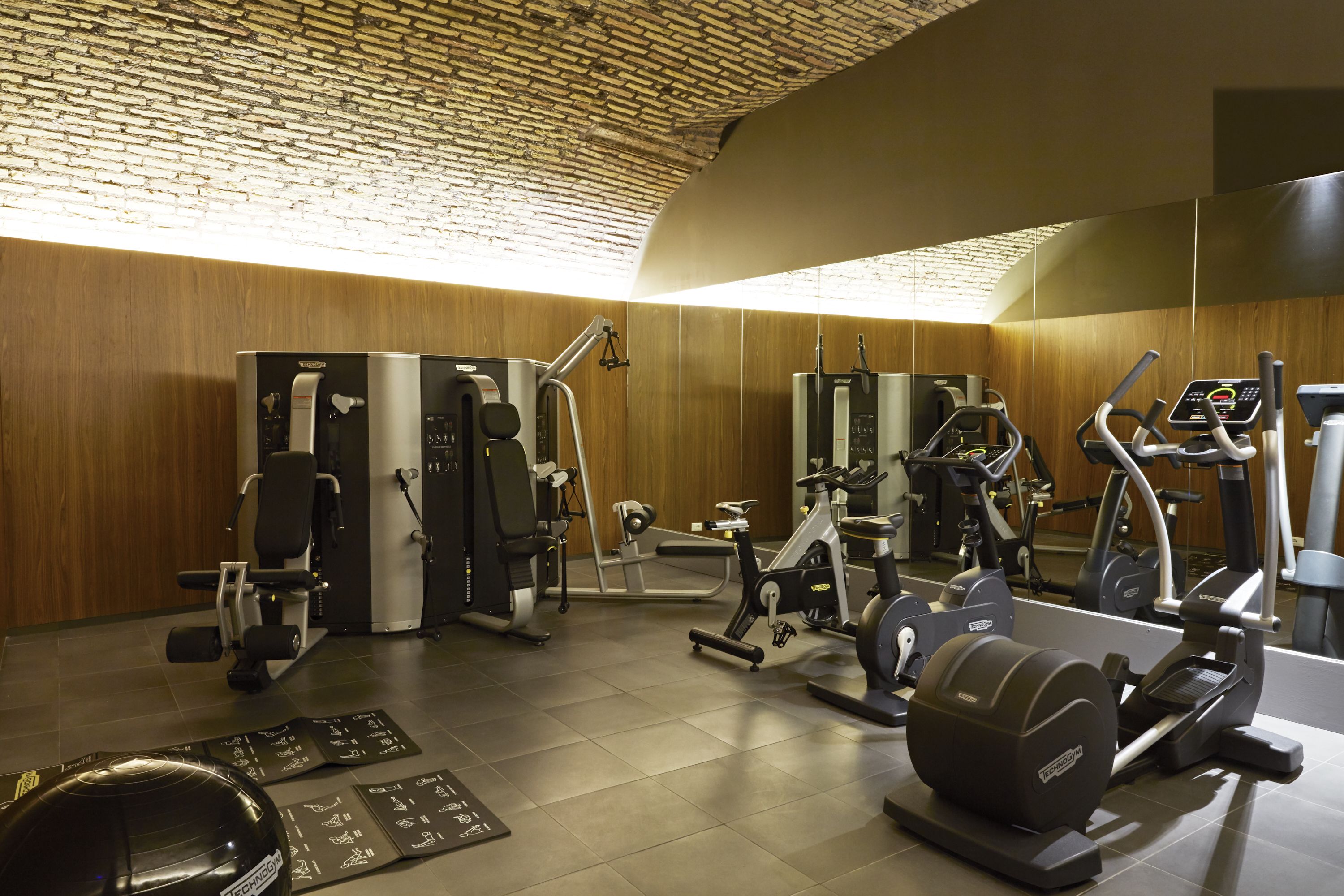Et fitnesscenter med forskellig træningsudstyr, herunder løbebånd, motionscykel og styrkemaskiner.