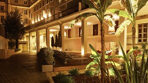 Un patio de hotel con sendero empedrado, zona de estar y plantas en macetas.