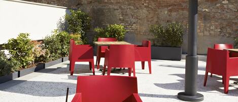 An outdoor dining area with red chairs and tables, a white lamp, and a variety of food and drinks.