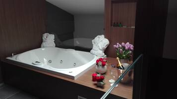 A modern bathroom with a large bathtub, a glass shower enclosure, and a wooden vanity with toiletries.