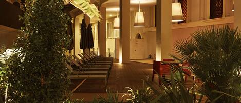 Een hotel lobby met een lange receptiebalie, meerdere zithoeken en een trap naar een hoger niveau.