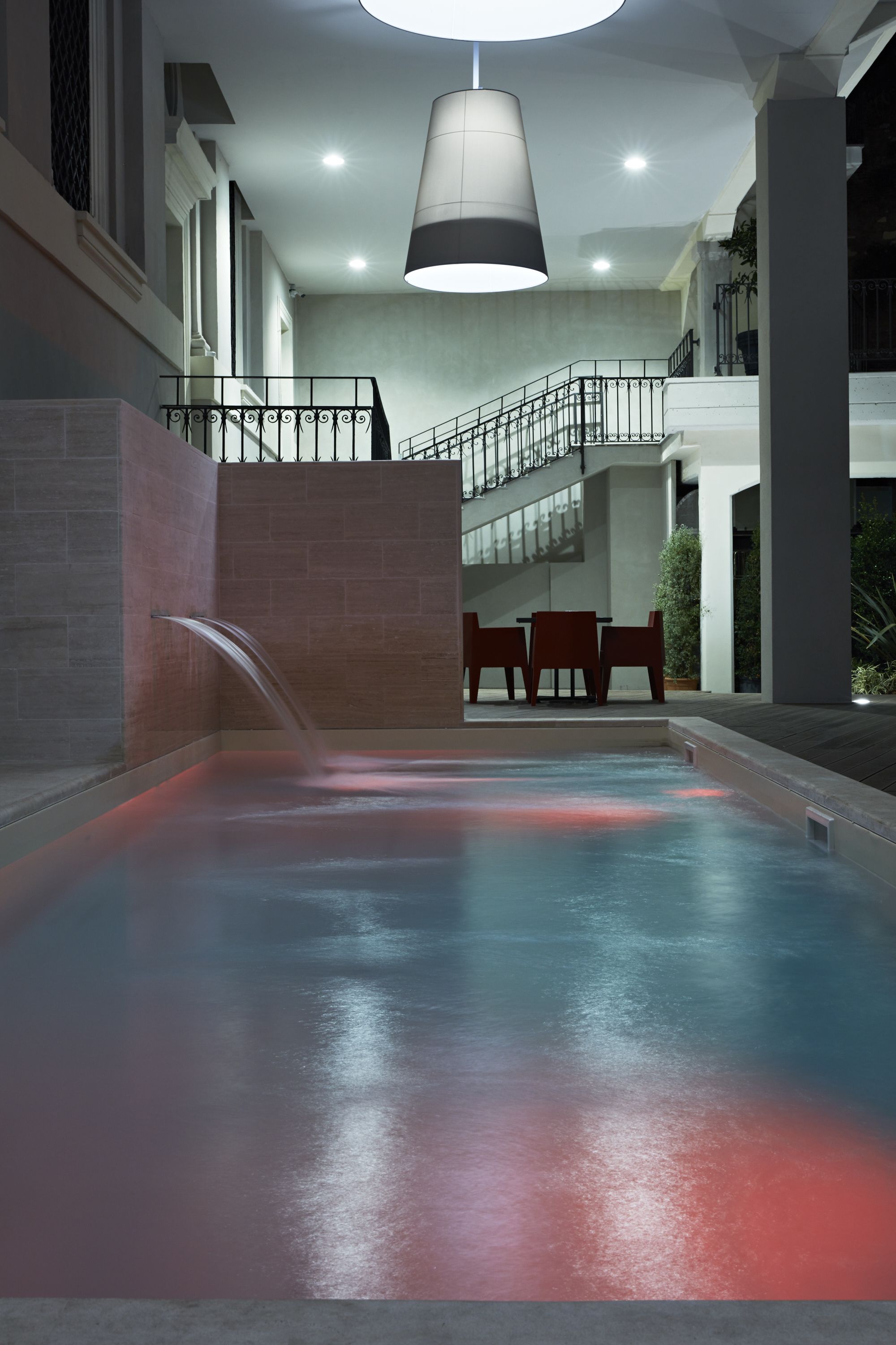 A pool area with a water feature, a staircase, and seating.