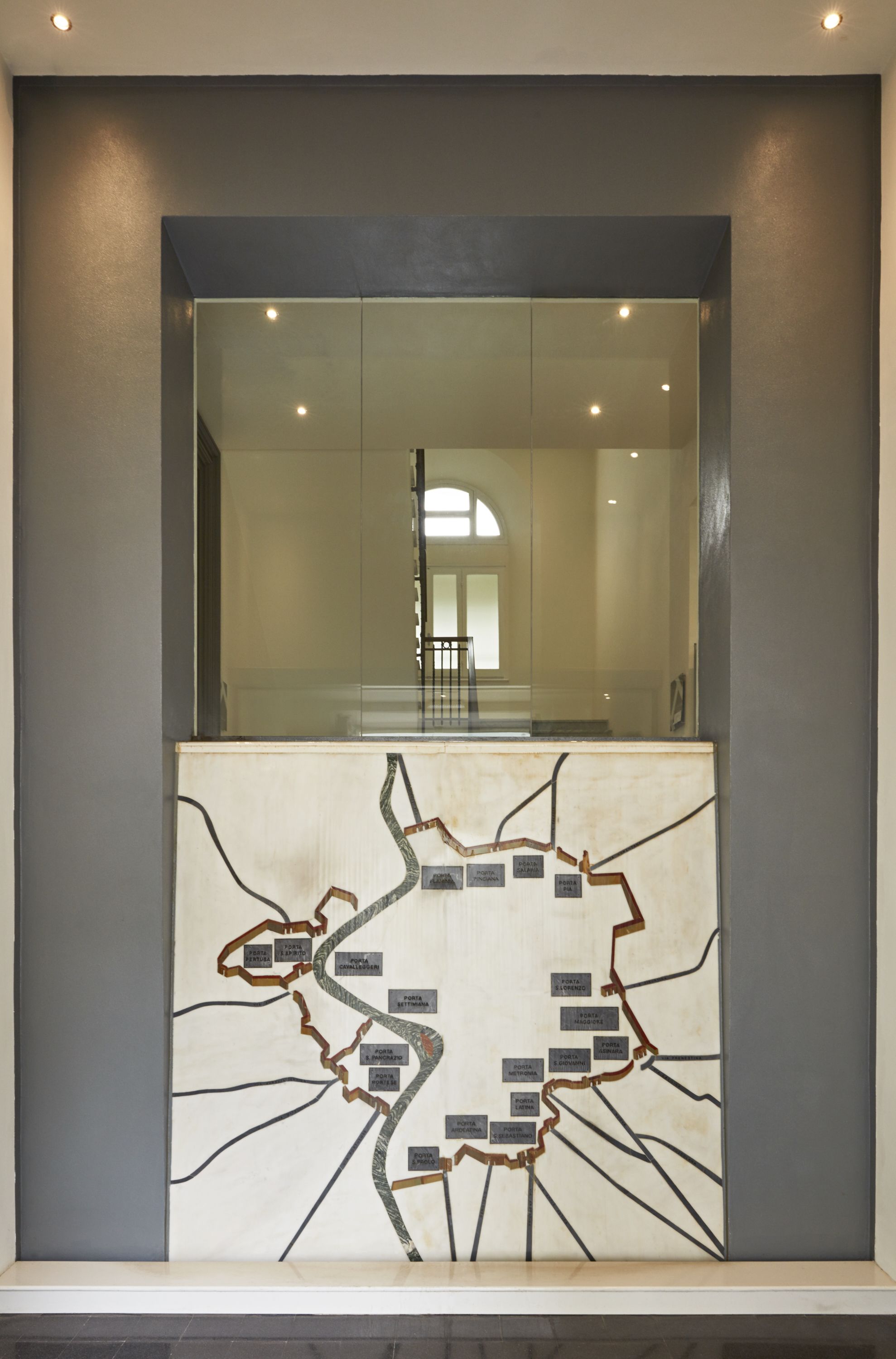 A modern interior with a glass partition and a map-like design on the wall.