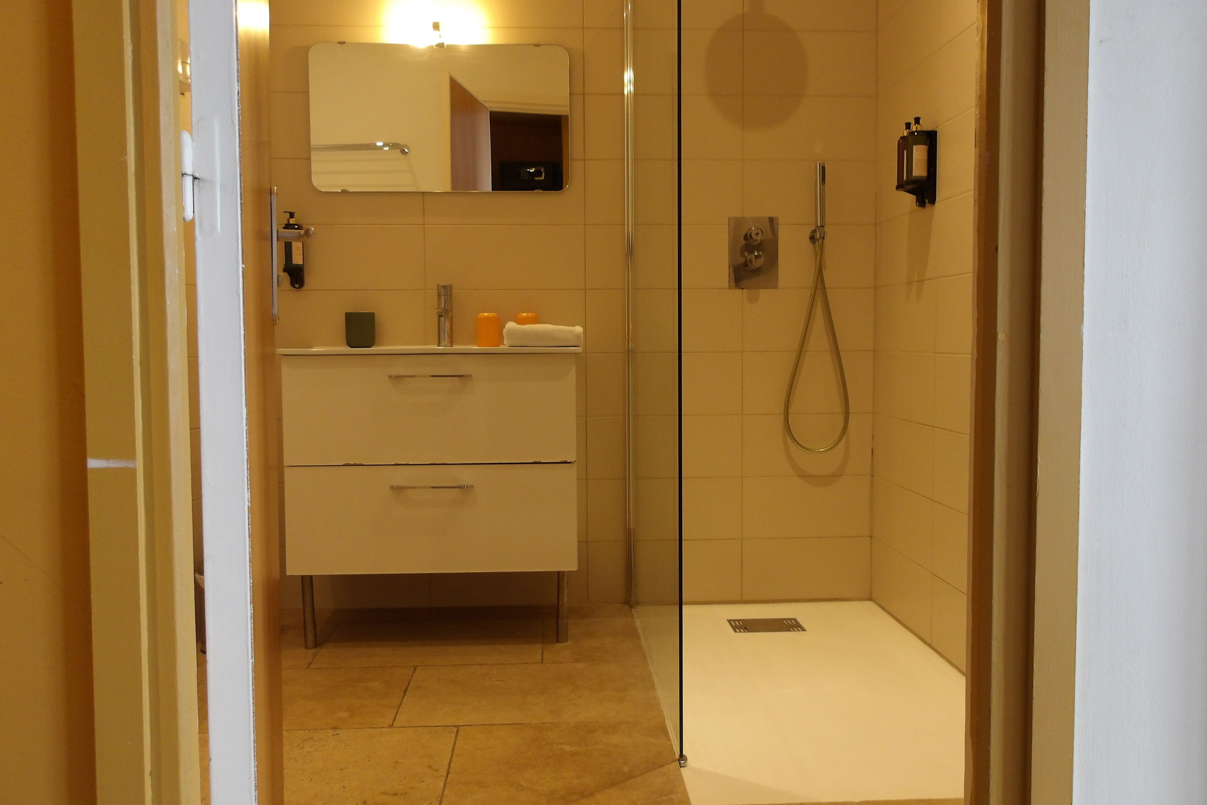 A bathroom with a shower, a sink, and a mirror.