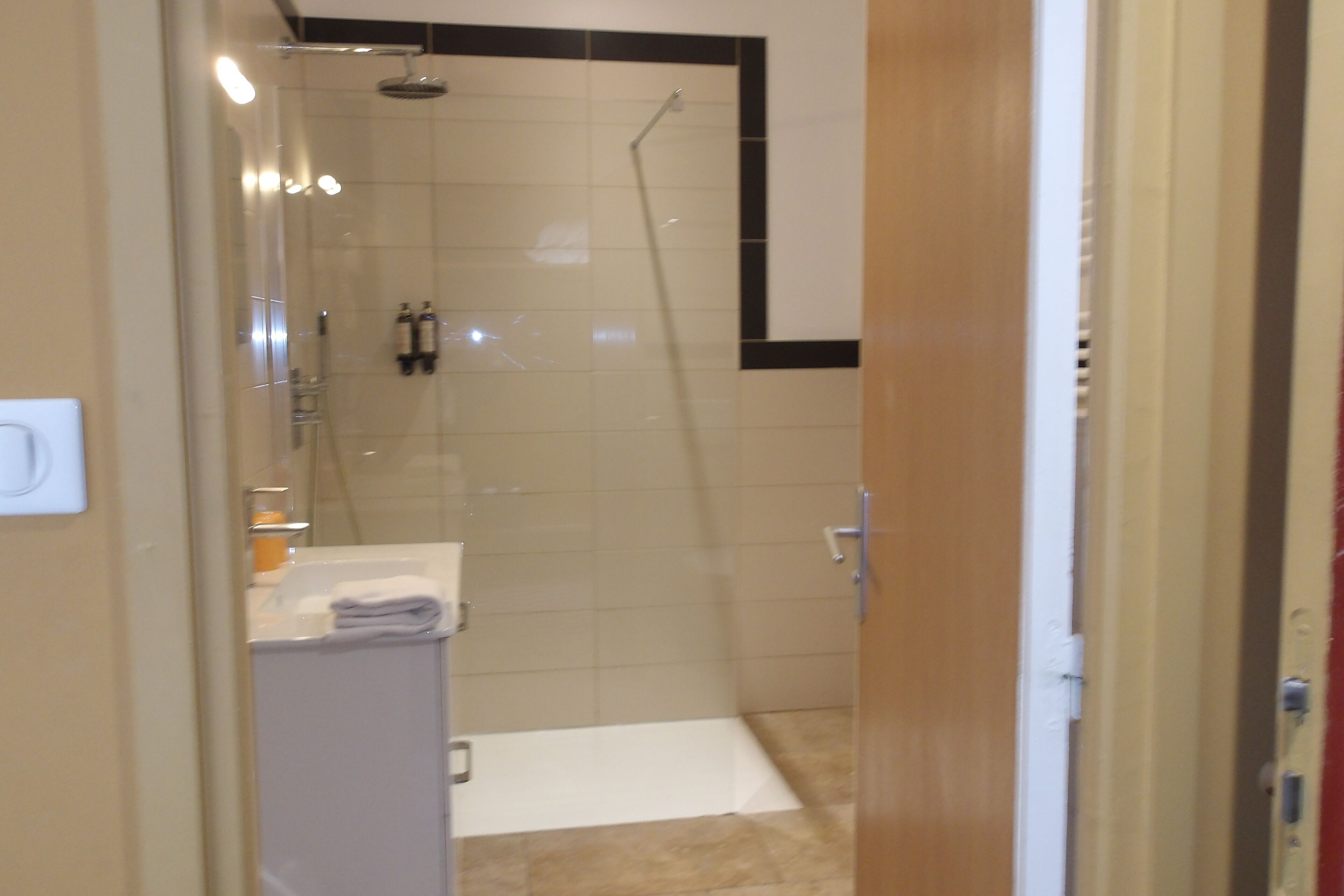 A bathroom with a glass-enclosed shower, a white sink, and a towel rack.