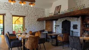 Interior de restaurante con paredes de piedra, vigas de madera y diferentes opciones de asientos.