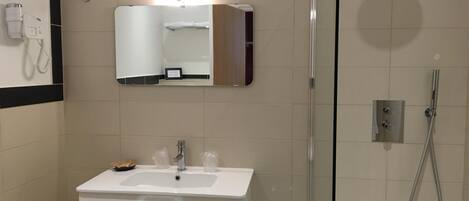 A modern bathroom with a white sink, mirror, and shower.