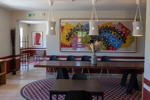 A conference room with a large table, chairs, a vase with flowers, and a colorful abstract painting on the wall. - La Maison des Ocres (Roussillon)