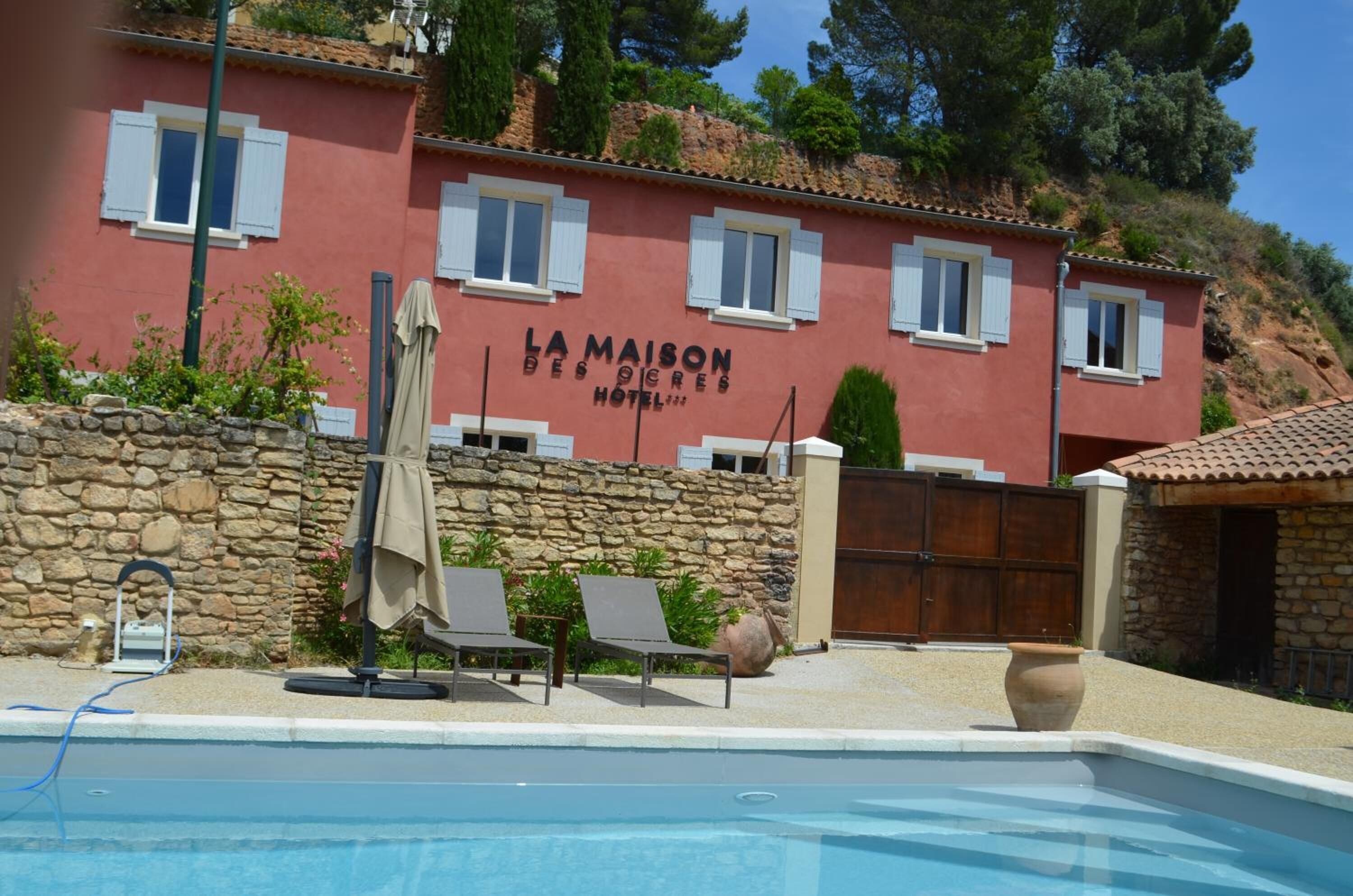 A red building with a pool, labeled "La Maison des Ogres Hotel".