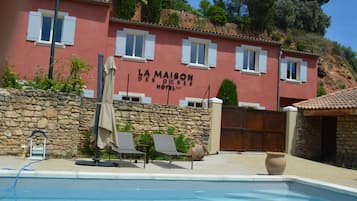 A red building with a pool, labeled "La Maison des Ogres Hotel".