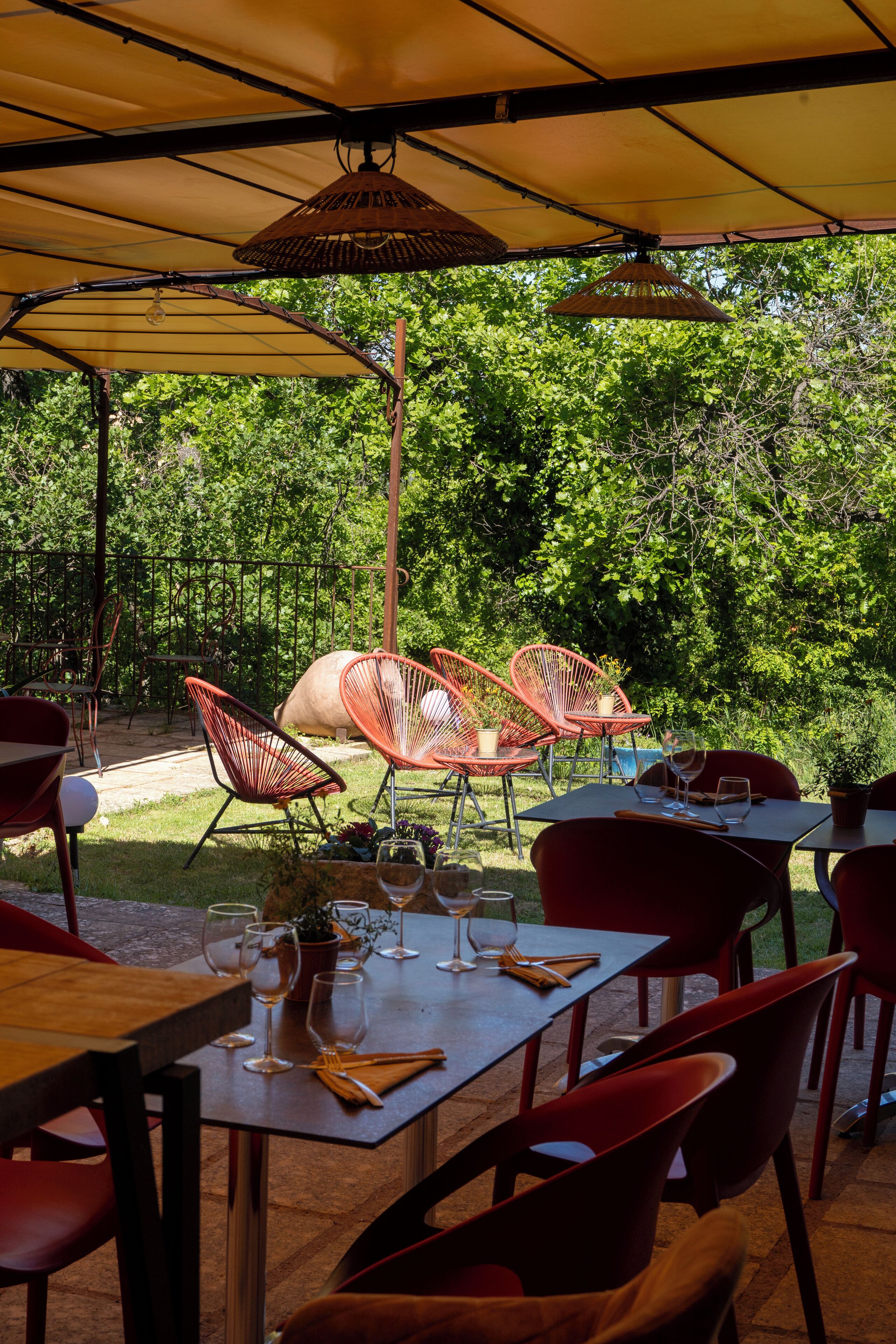 Un espace extérieur aménagé pour les repas, avec des tables, des chaises, des parasols et un cochon en arrière-plan.