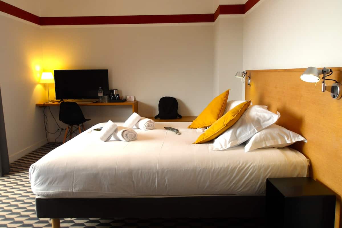 A hotel room with a bed, a television, a desk, and a chair.