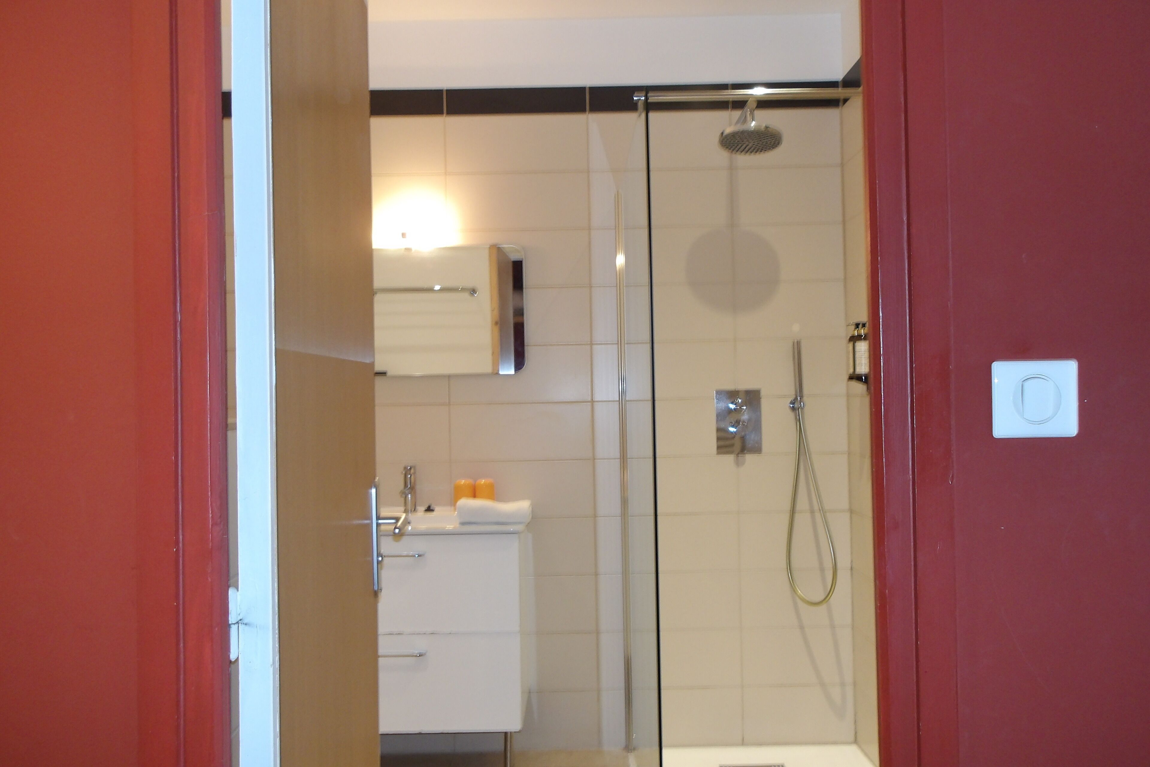 Un baño moderno con cabina de ducha de vidrio, un lavabo blanco y un perchero para toallas.