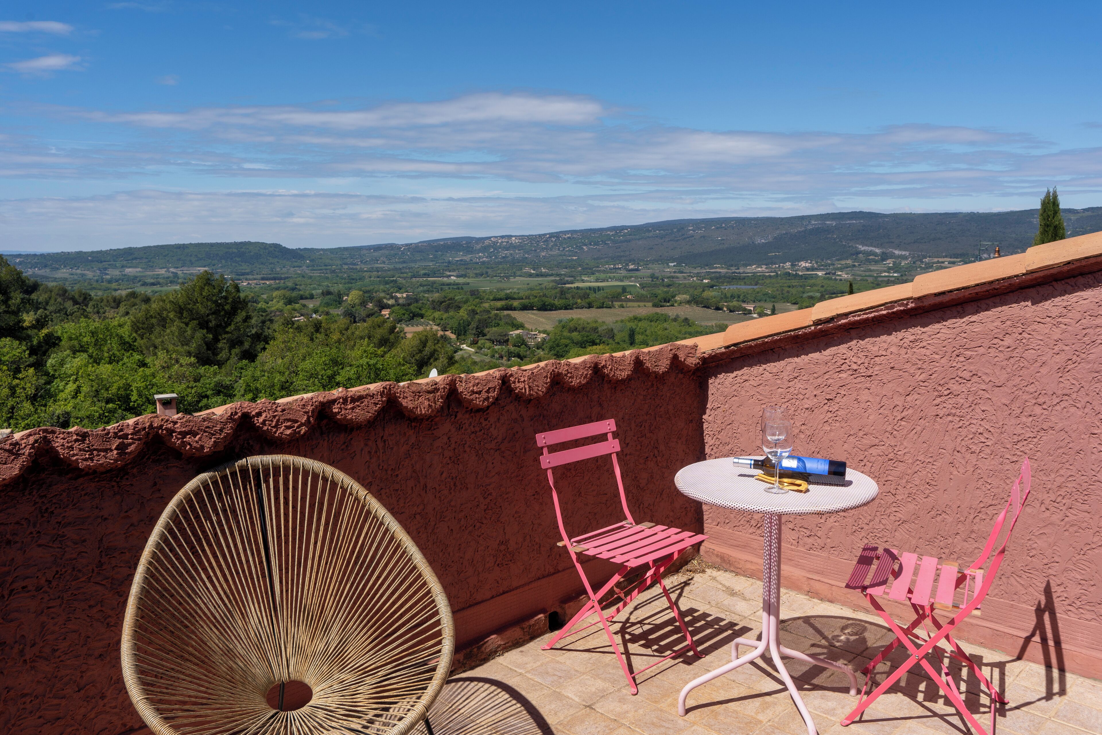 Une terrasse avec des chaises en osier, une table et une vue sur la campagne.