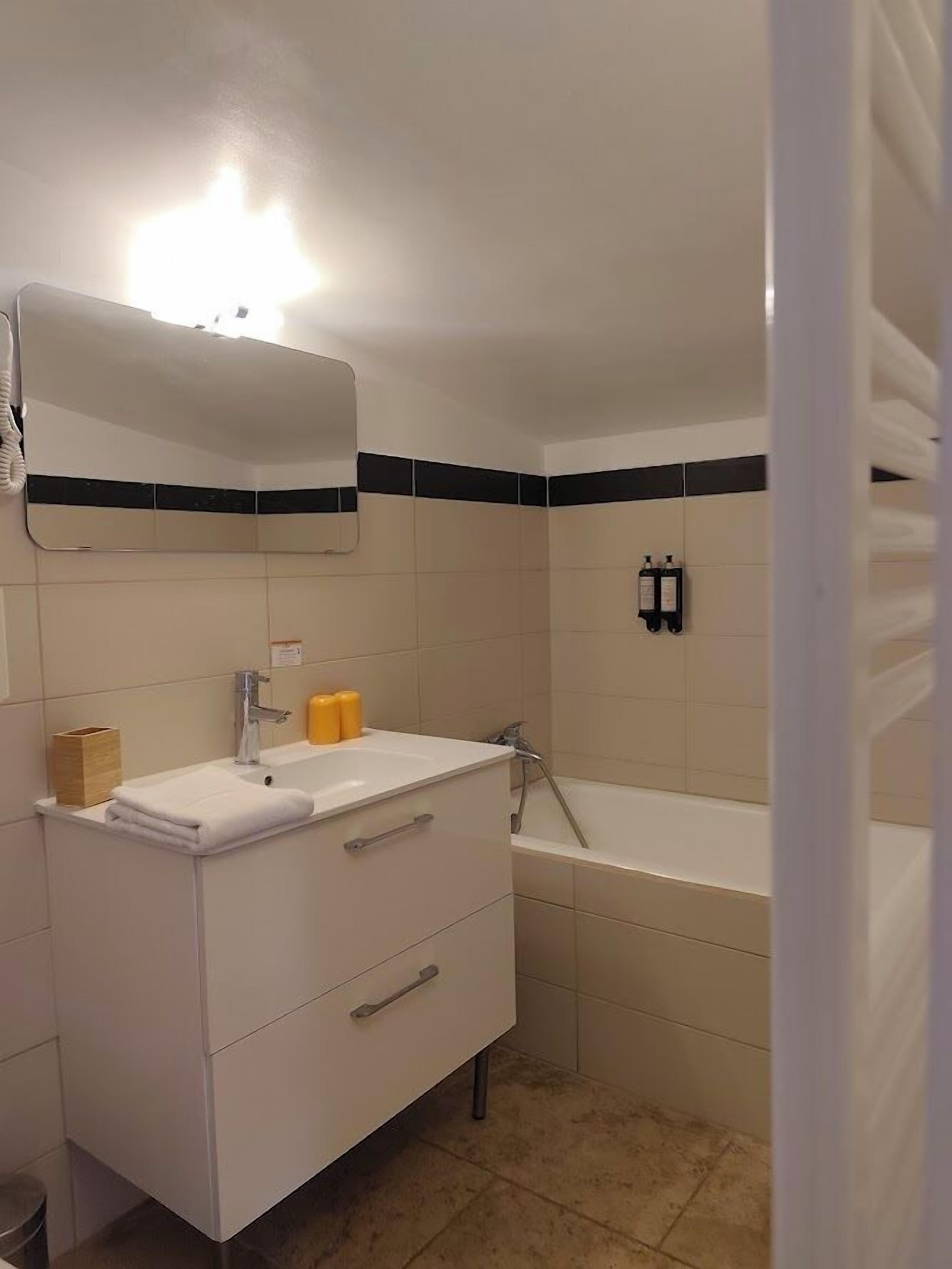 Ein Badezimmer mit weißem Waschtisch, einem Spiegel, einem Waschbecken und einer Badewanne.