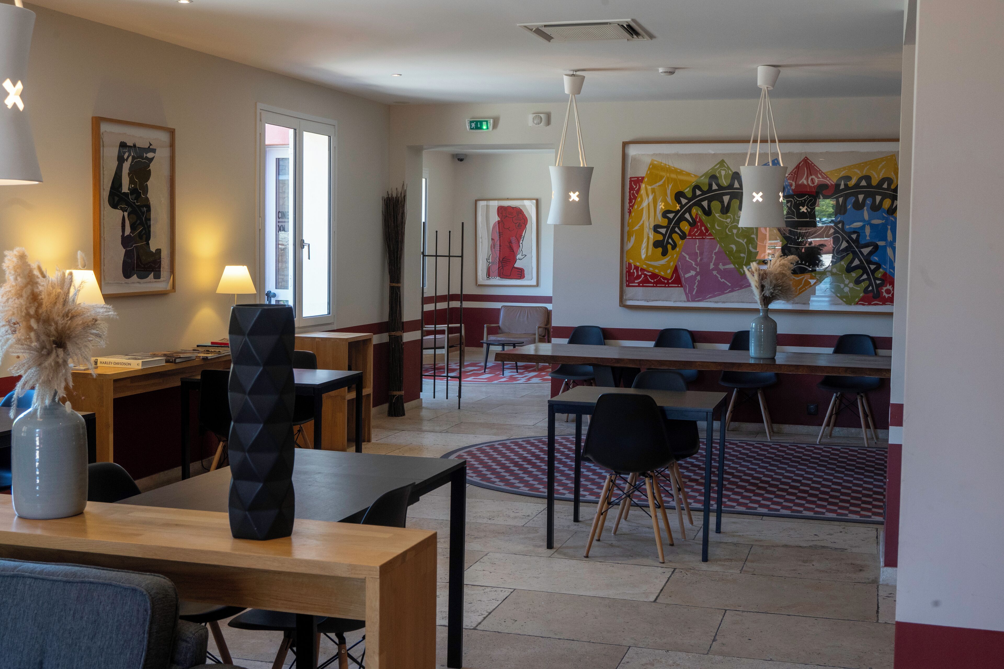 Un comedor moderno con mesas y sillas, obras de arte en las paredes y un ventanal grande.