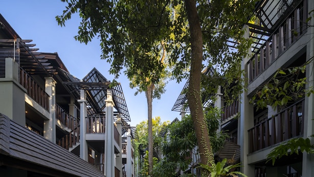Un patio con una fuente central rodeado de exuberante vegetación y edificios modernos con balcones.