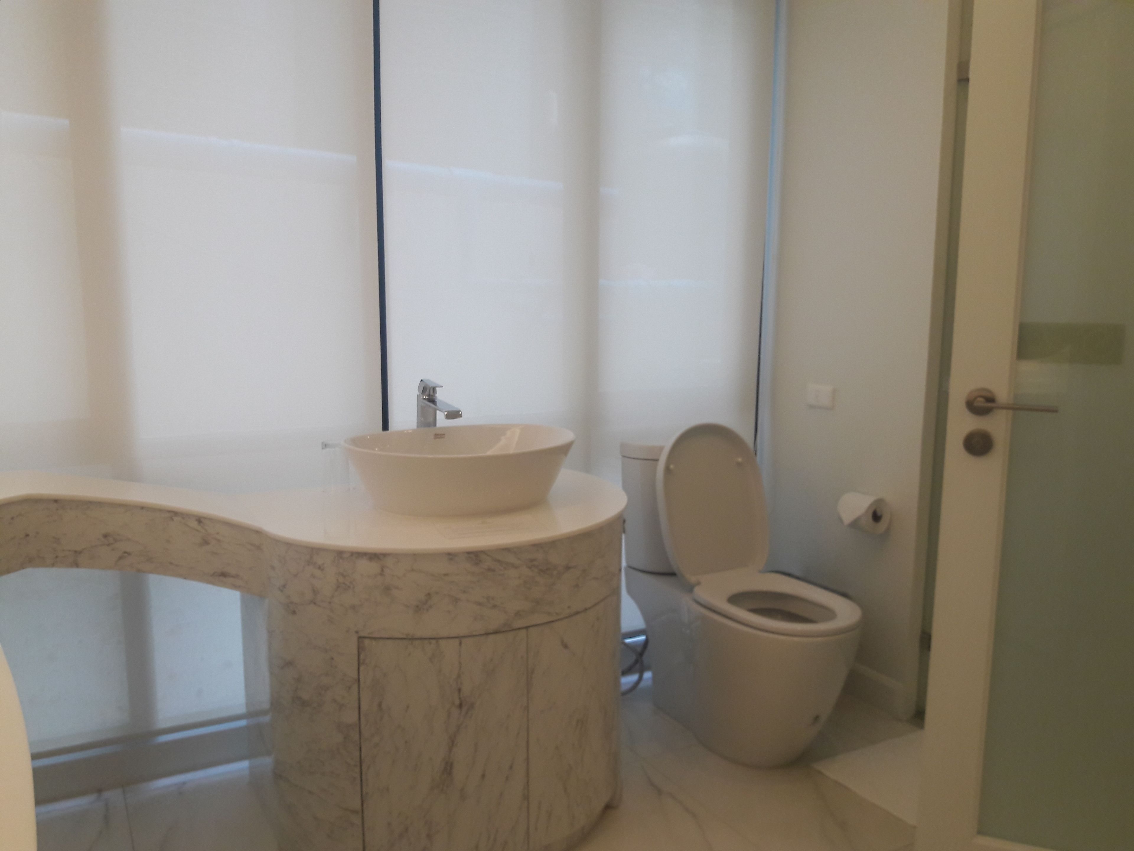 A bathroom with a marble sink, a toilet, and a glass shower enclosure.