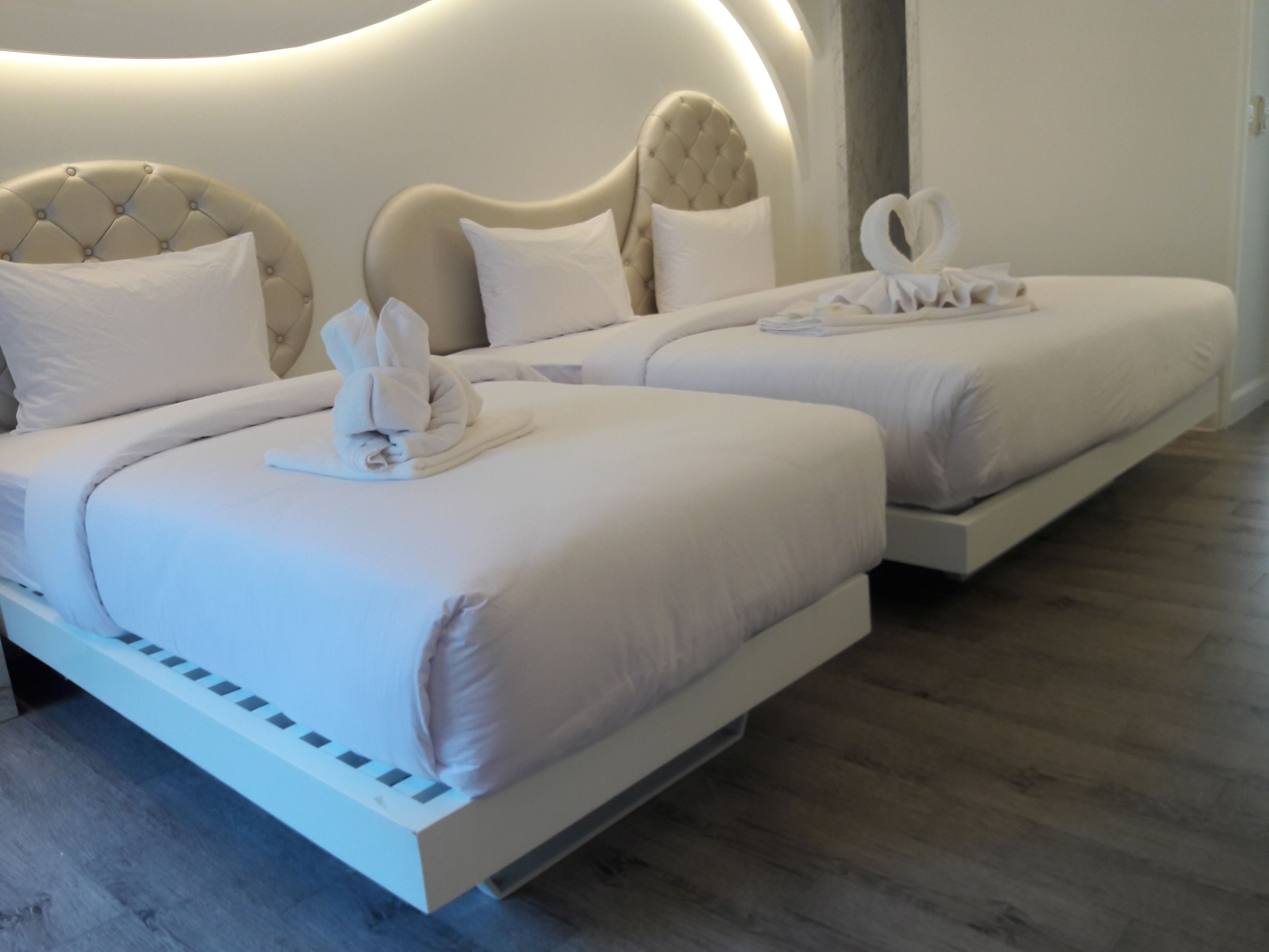 A modern hotel room with two beds, each with a tufted headboard and white bedding.