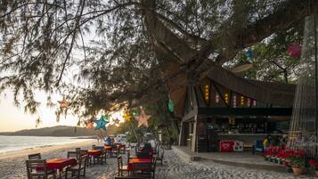 Un ristorante sulla spiaggia con posti a sedere all'aperto, un bar e vista mare.