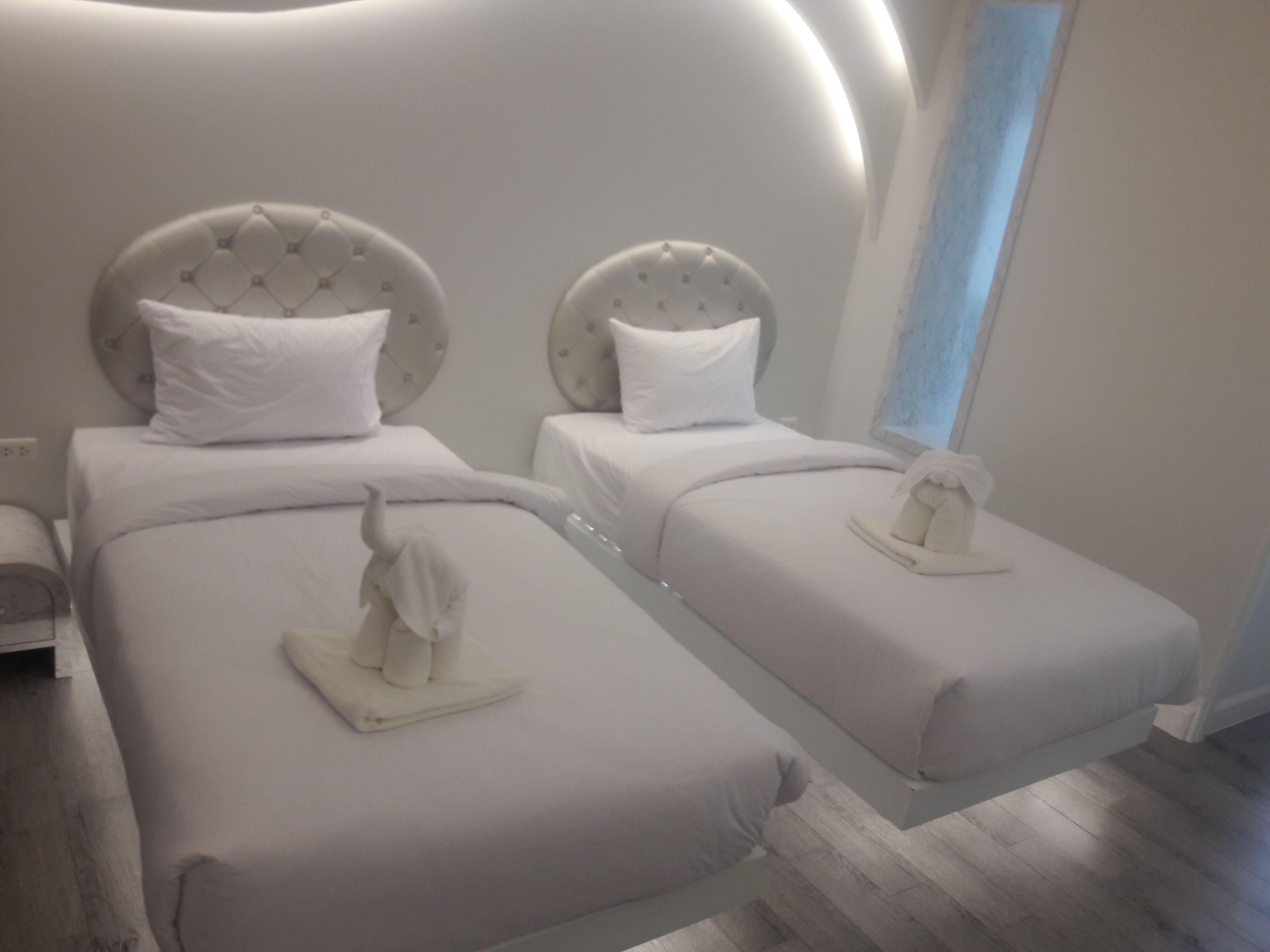 A modern hotel room with two beds, each with a headboard and pillow.