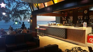 Zona de bar con vista al mar, asientos y una barra con diversos artículos.