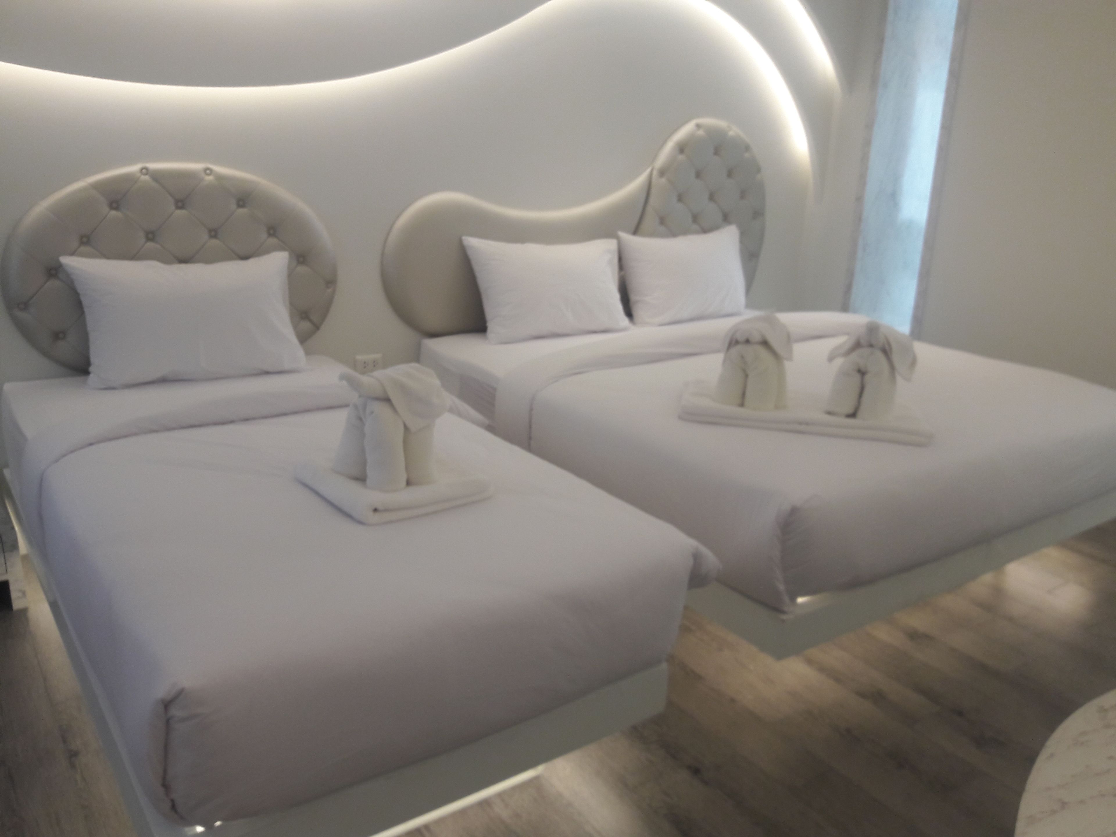 A modern hotel room with two beds, each with a tufted headboard and white bedding.