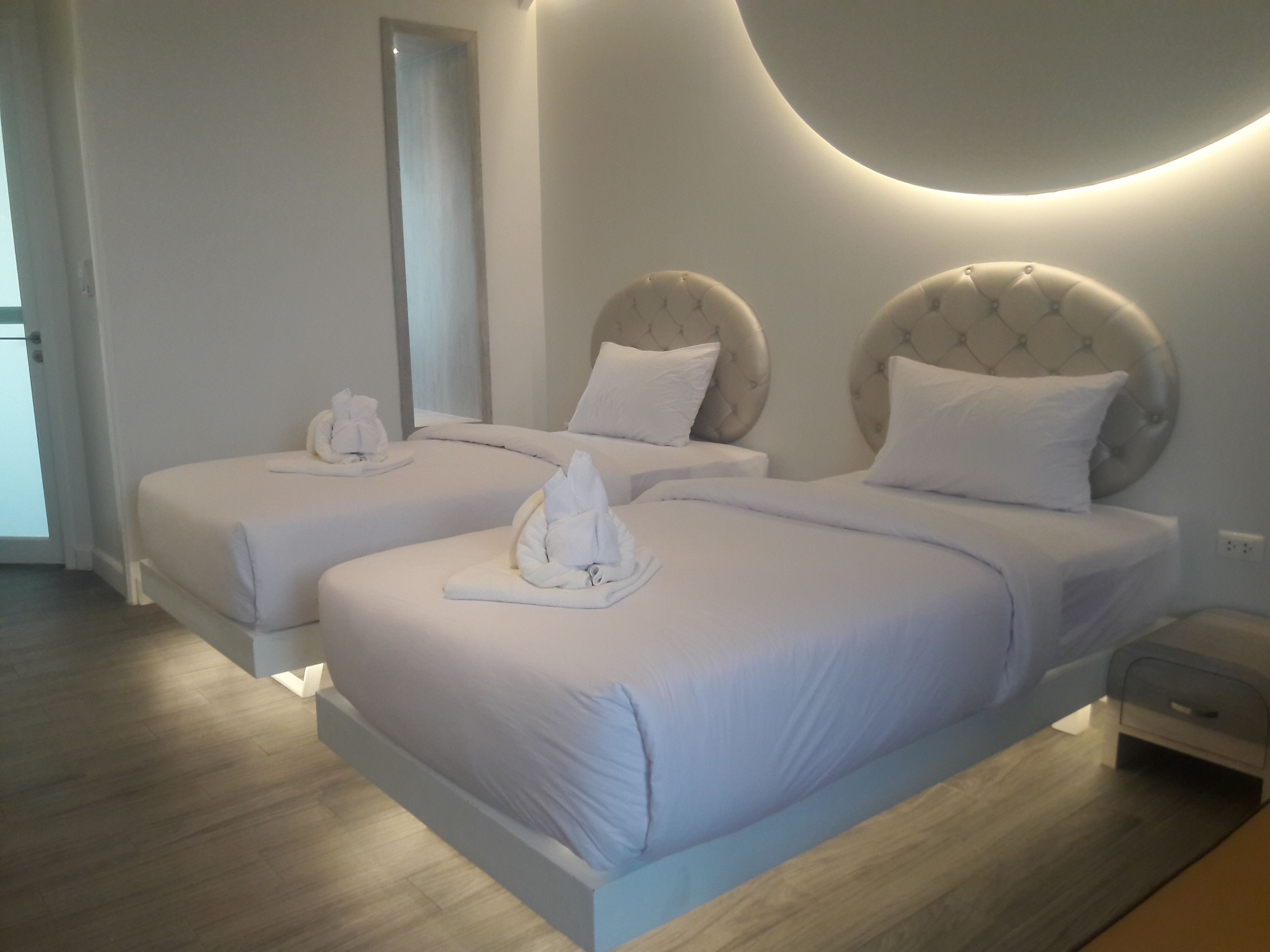 Una camera d'albergo con due letti, ognuno con testiera, comodino e lampada.