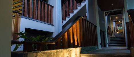 A multi-level interior with a staircase, wooden railings, and a stone wall.