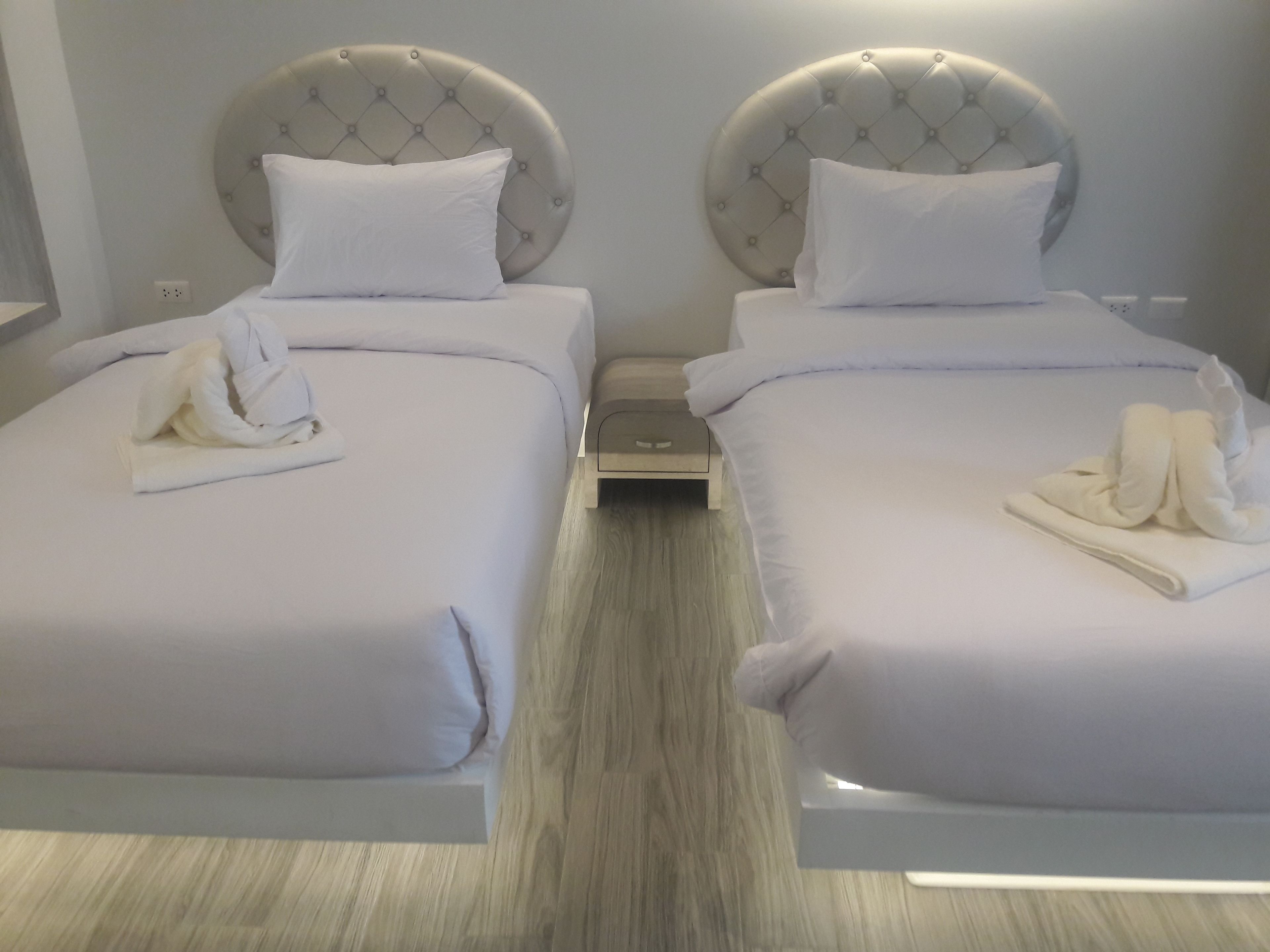 A hotel room with two beds, each with a tufted headboard and white bedding.