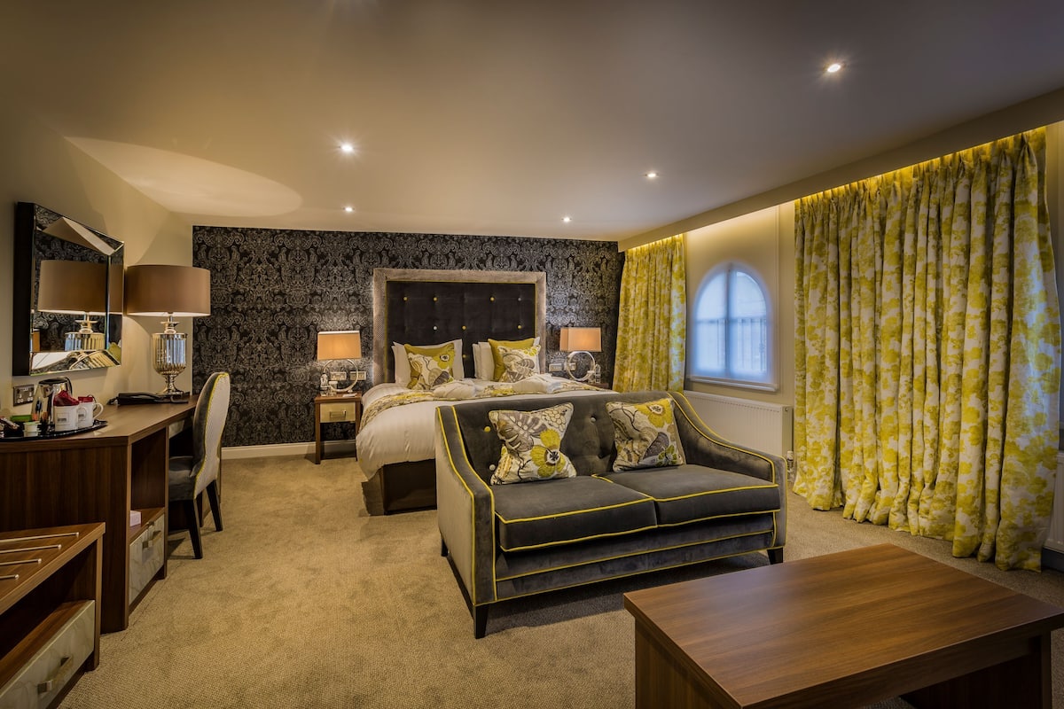 Une chambre d’hôtel avec un lit, un canapé, un bureau et une télévision.