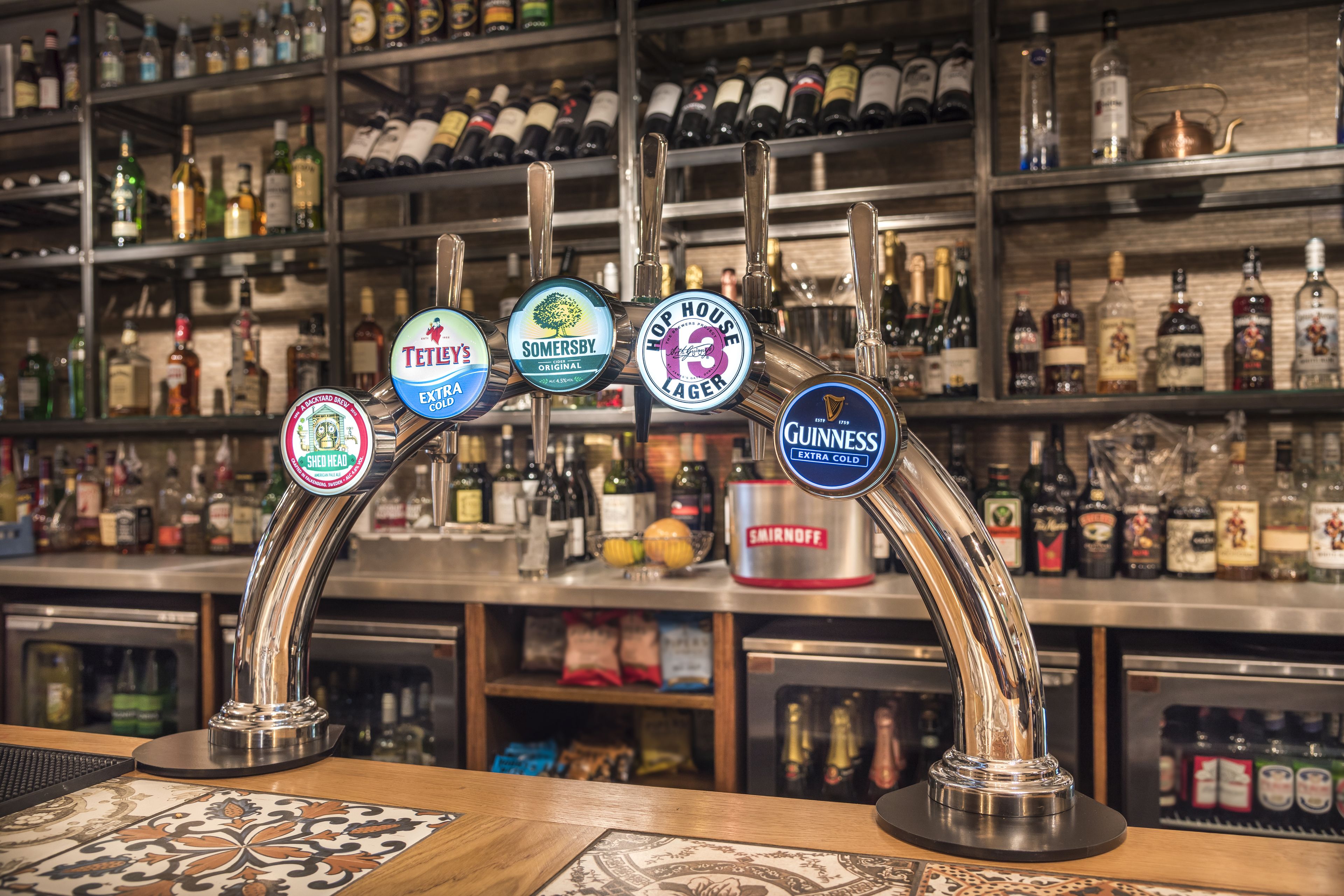 A bar with multiple taps, including brands like Tennent's, Somersby, and Guinness.