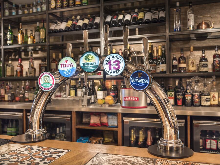 A bar with multiple taps, including brands like Tennent's, Somersby, and Guinness.