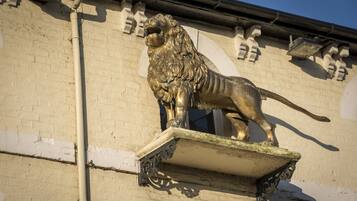A lion statue mounted on a wall with a white and beige brick facade.