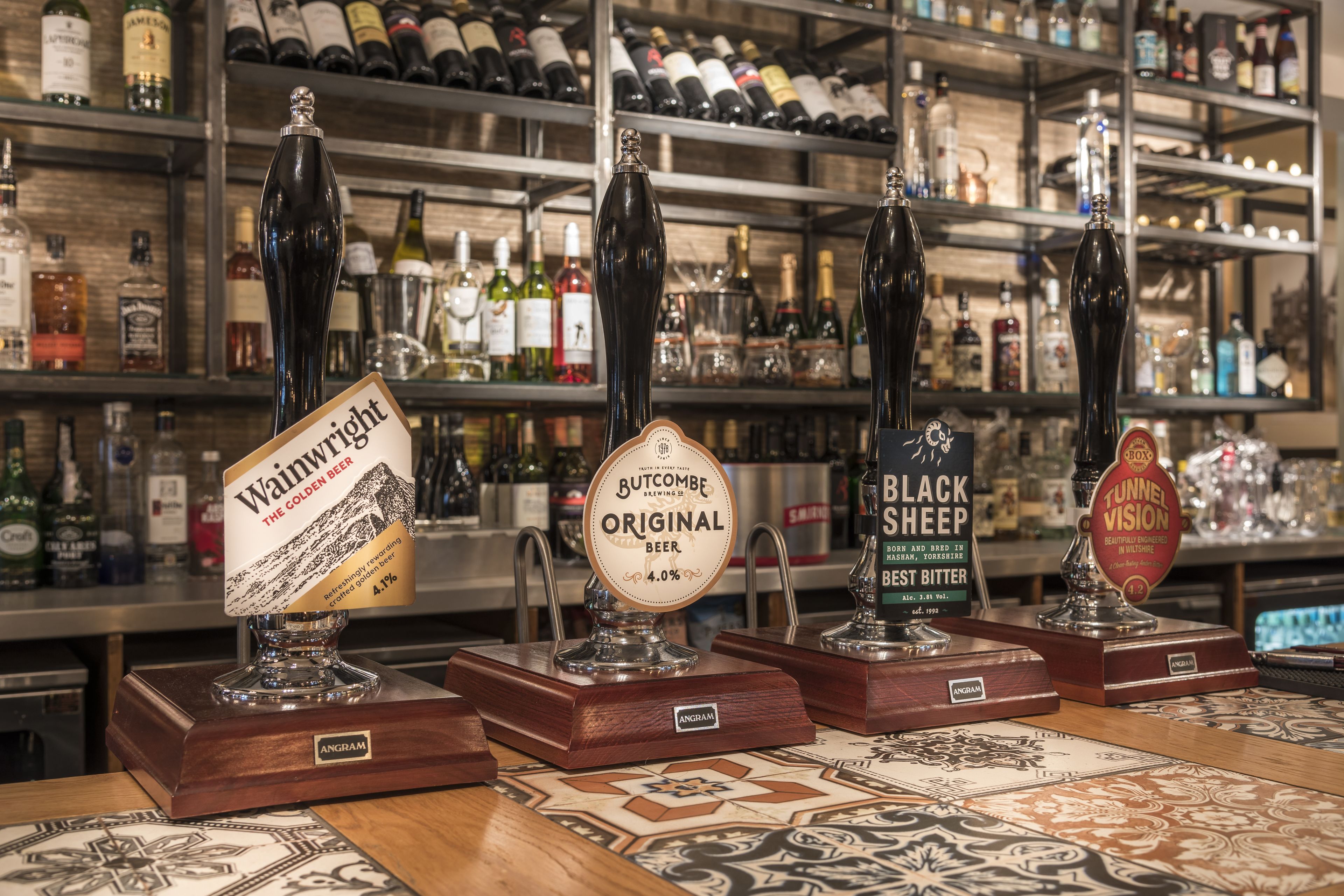 A bar with four beer taps labeled with different brands.