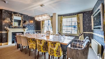 A dining room with a long table, chairs, and a chandelier.