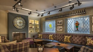 A cozy lounge area with a large clock, a fireplace, and a seating area with a sofa and armchairs. - The Golden Lion Hotel, St Ives, Cambridgeshire (St Ives)