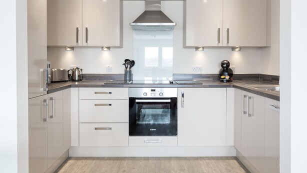 A modern kitchen with white cabinets, a Bosch oven, and stainless steel appliances.