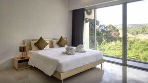 Een moderne hotelkamer met een groot bed, een nachtkastje en uitzicht op groen buiten het raam.