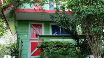 Ein grünes Haus mit roter Tür und kleiner Veranda.
