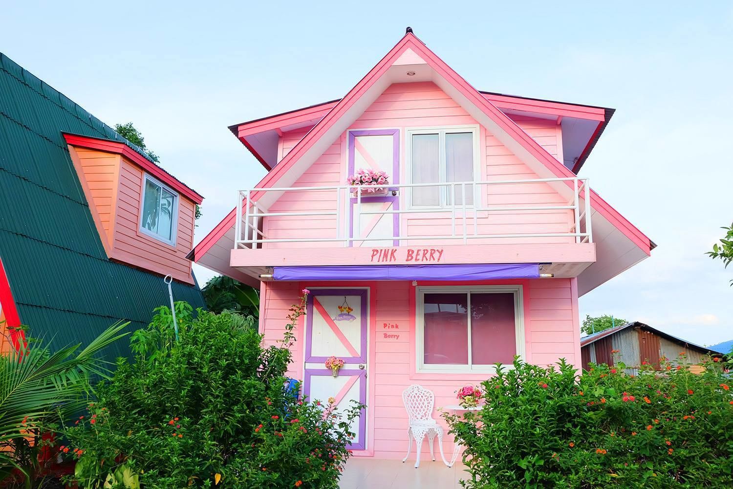 Une maison rose avec un balcon et une enseigne sur laquelle on peut lire « Pink Berry ».