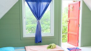 Una habitació amb dos llits, una finestra amb cortines blaves i una porta vermella.