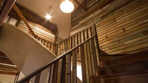 A wooden staircase with a metal railing, leading to a higher floor. - Here Hostel (Bangkok)